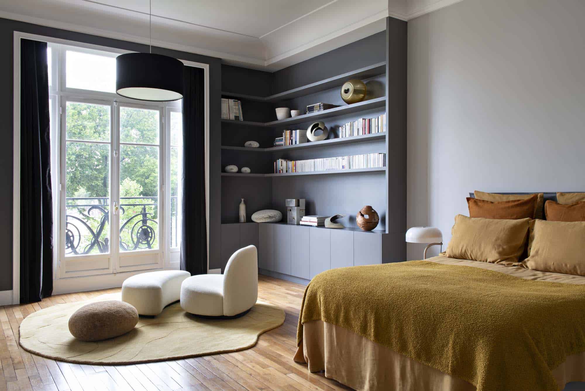 Chambre au couvre-lit ocre face à une bibliothèque sur mesure gris sombre toute hauteur