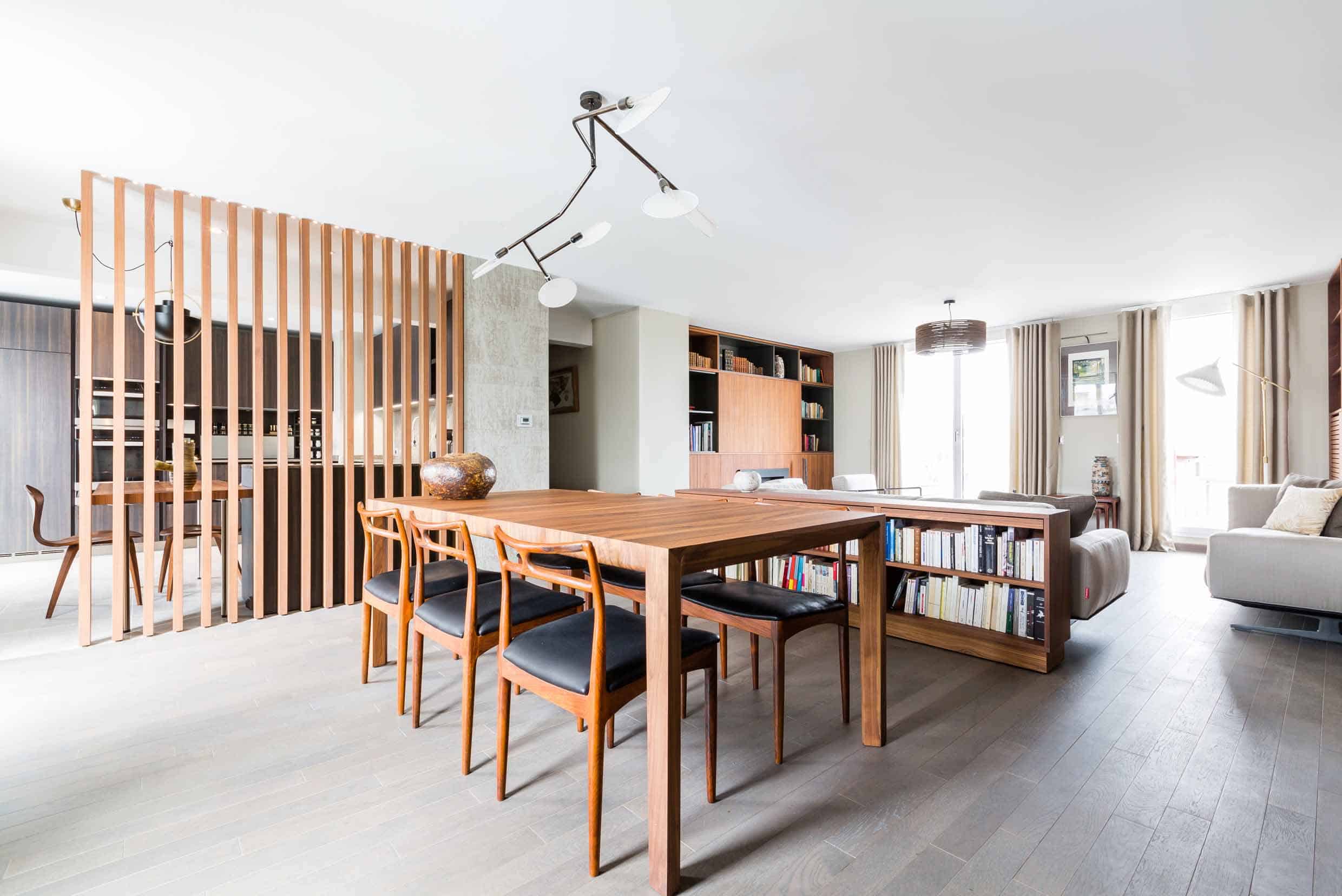 Salle à manger séparée du séjour par un claustra en tasseaux de bois, longue table et perspective traversante