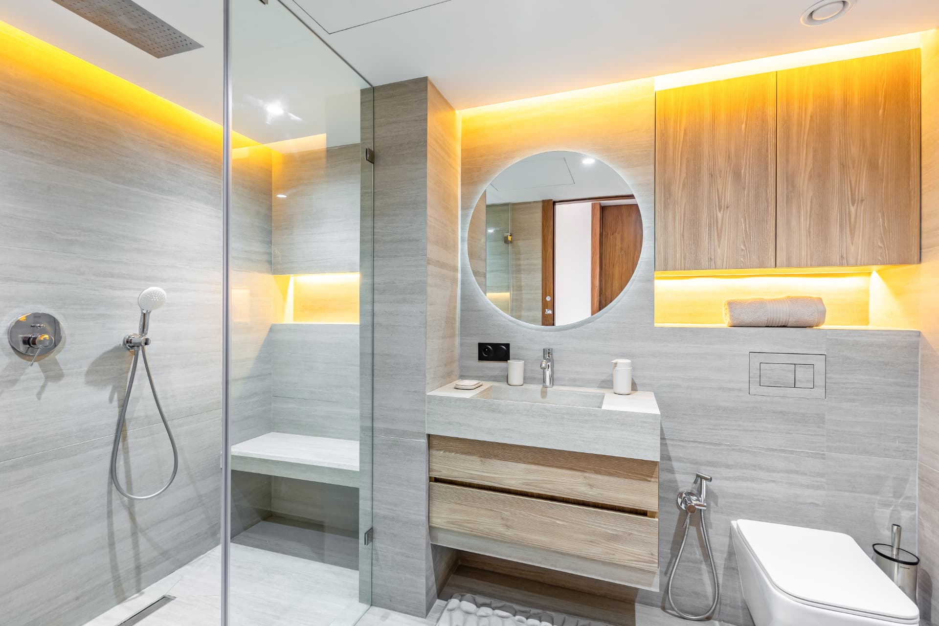 Salle de bains : douche à l'italienne, double vasque en pierre et miroir rond rétroéclairé