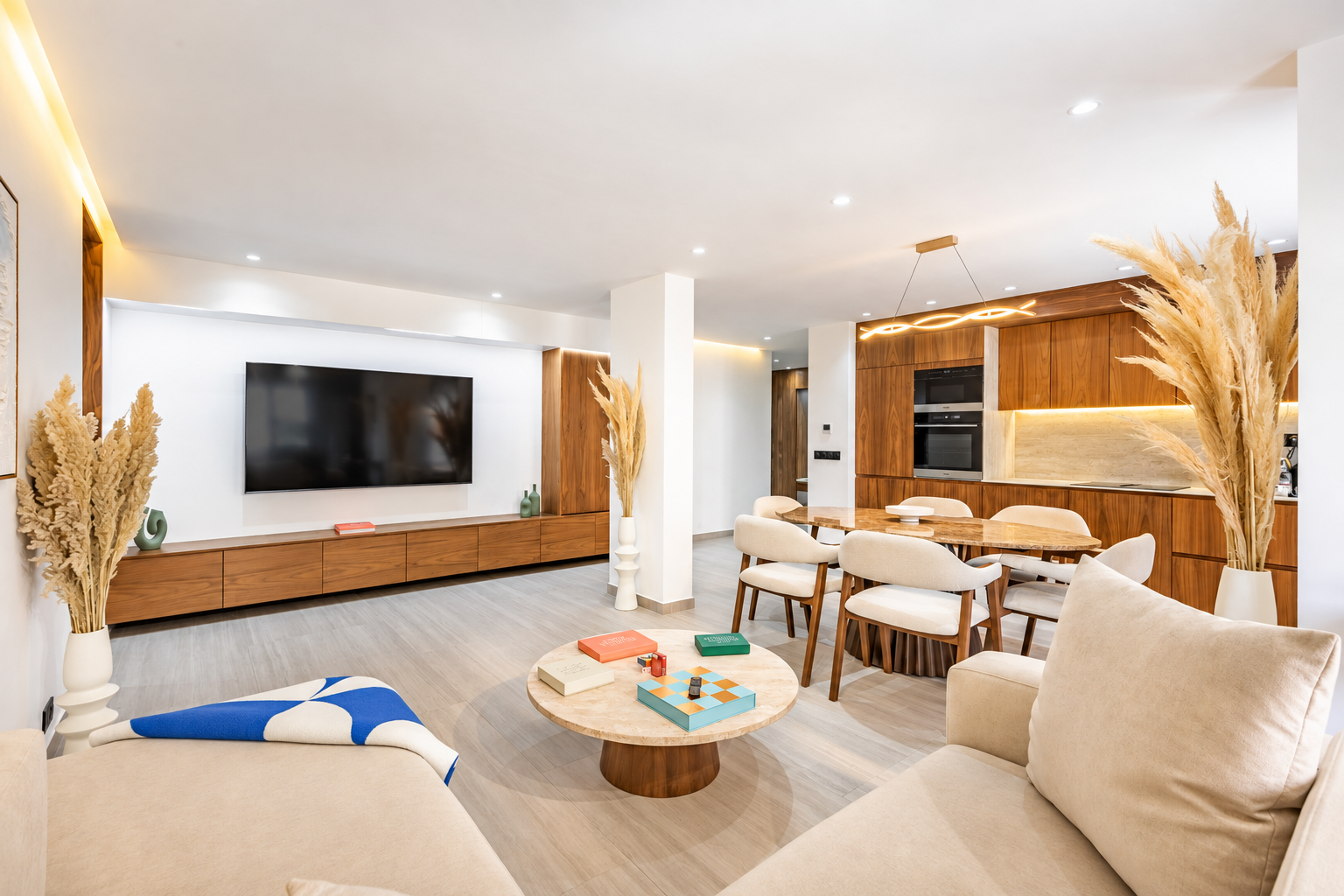 Salon ouvert : meuble TV en noyer, table basse en travertin, salle à manger et cuisine en bois
