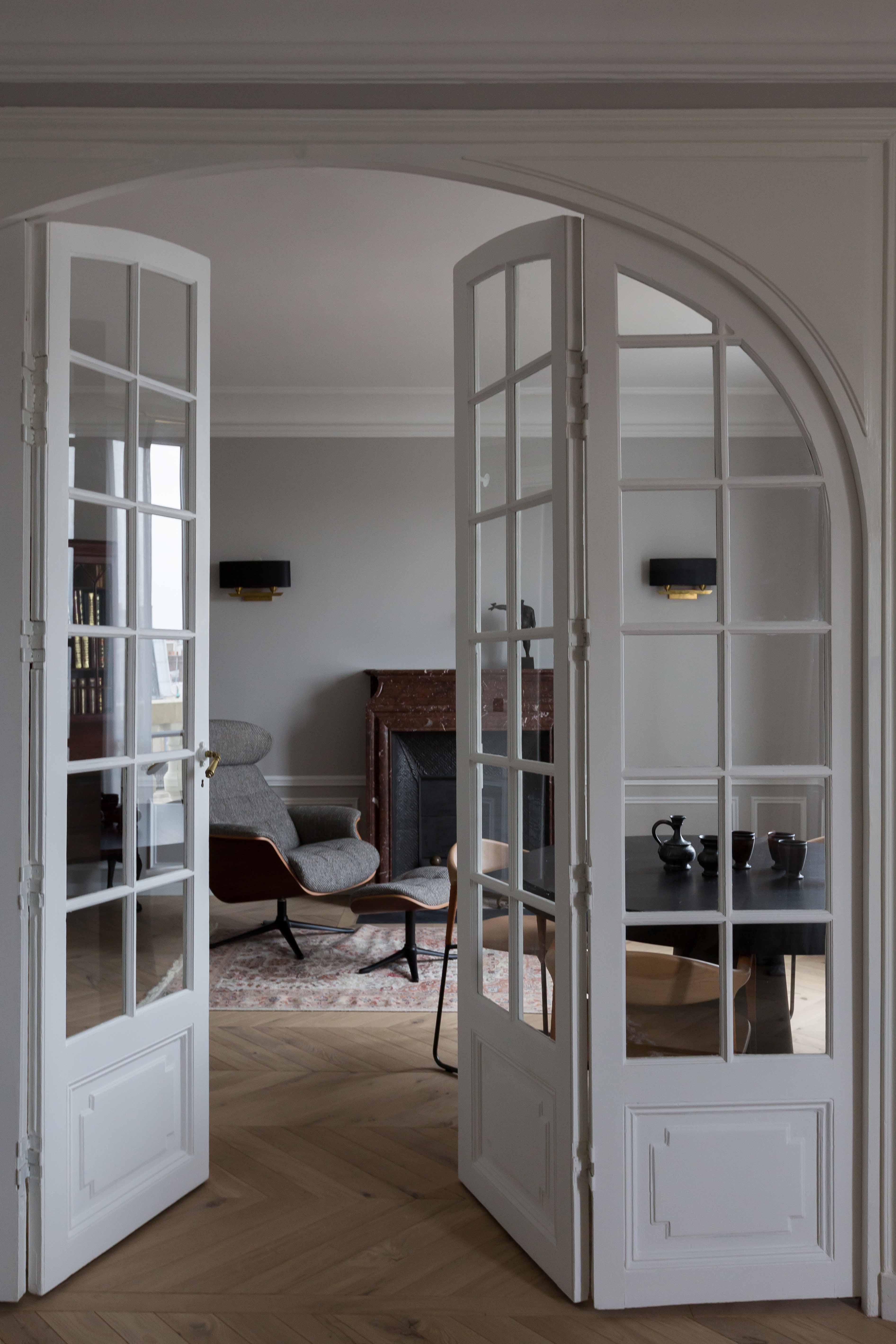 Portes vitrées cintrées ouvertes, vue traversante vers la pièce de réception au parquet en point de Hongrie
