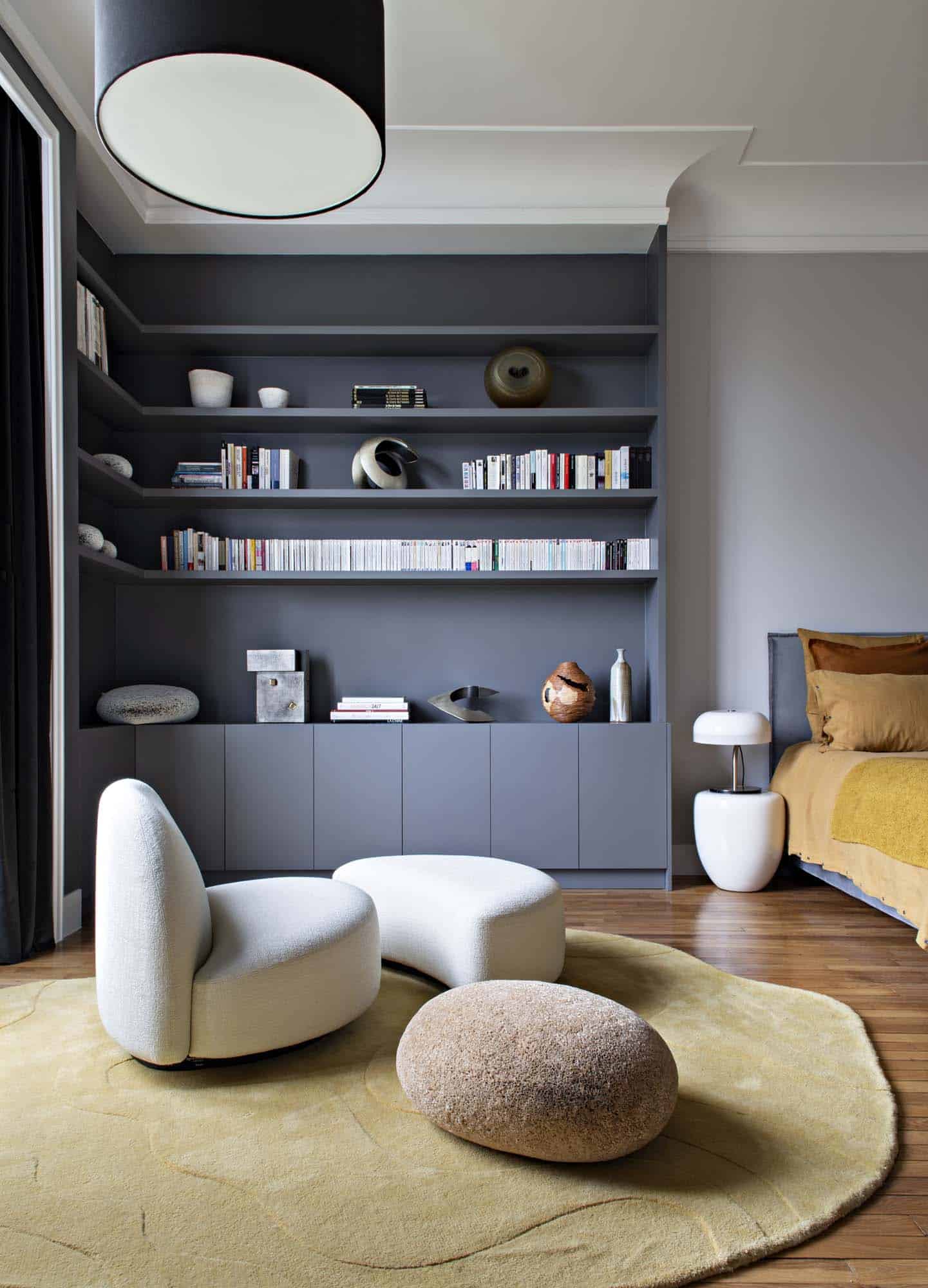 Bibliothèque sur mesure gris sombre et ses rangements bas, ouverte sur la chambre