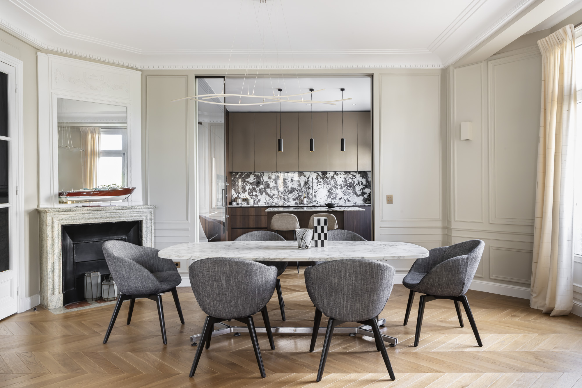 Salle à manger ouverte sur la cuisine, table ovale en marbre et fauteuils gris