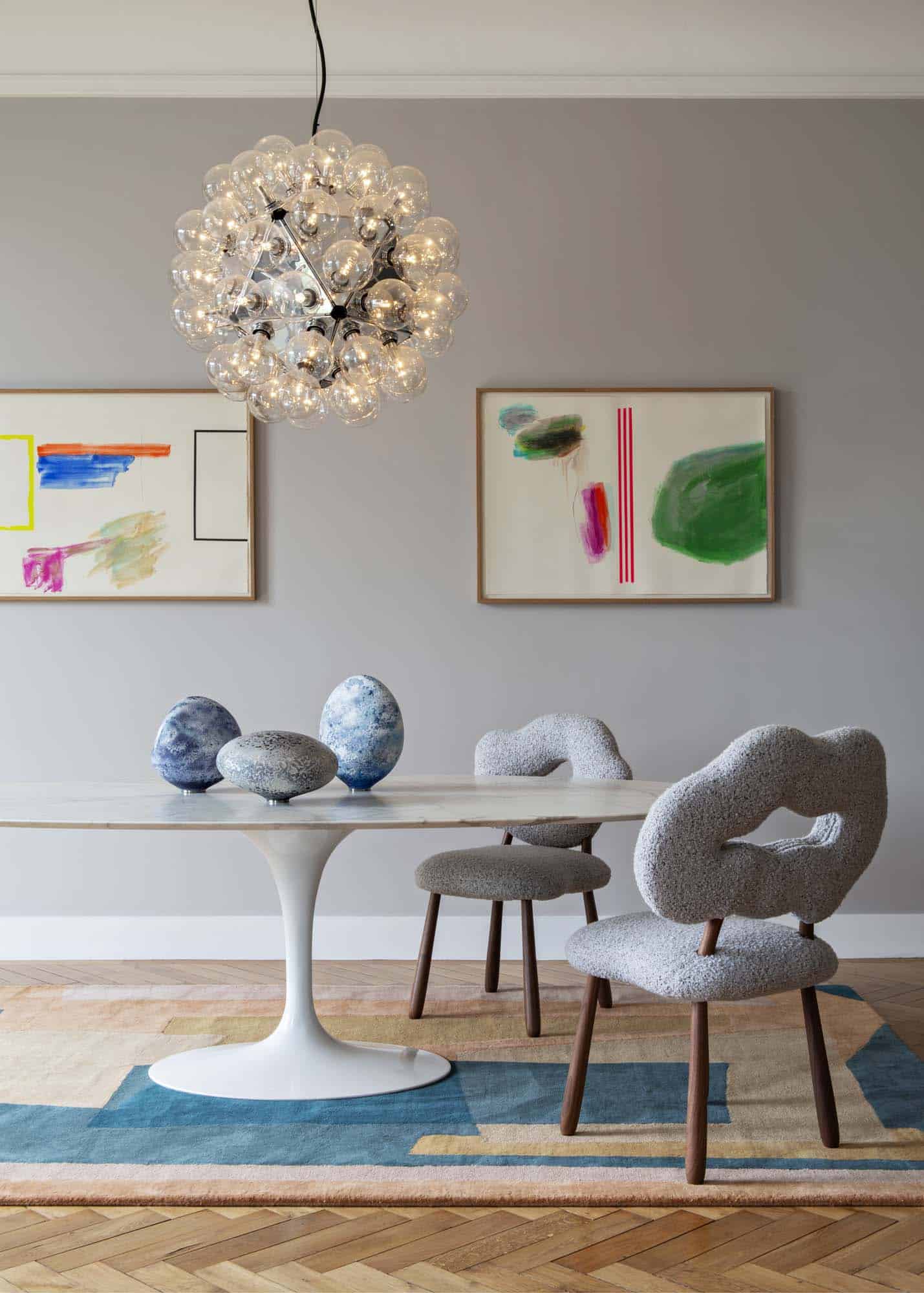 Salle à manger avec table ronde à piètement central, chaises sculpturales et suspension à bulles de verre