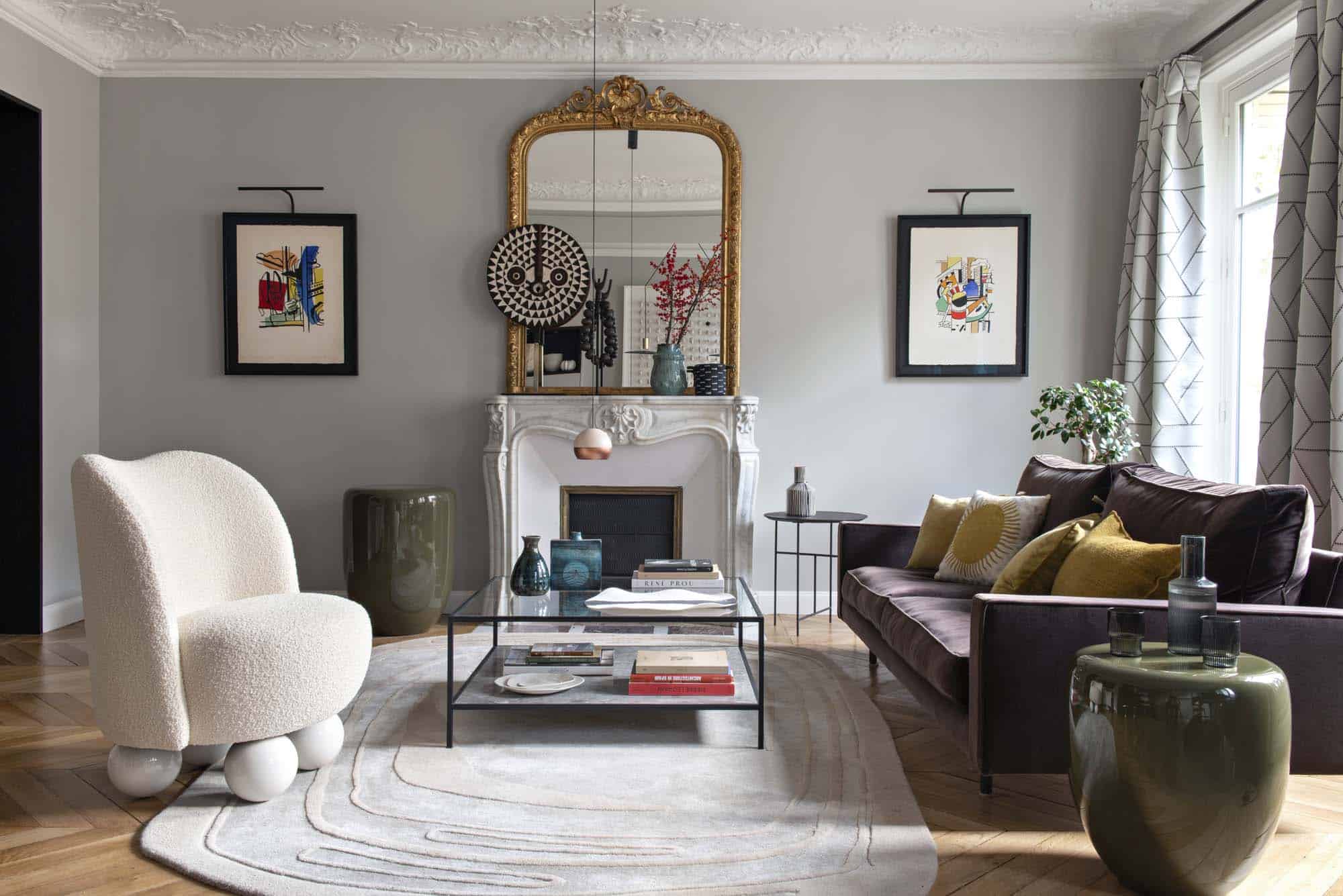 Pièce de réception avec cheminée en marbre, miroir doré, assises basses et tapis clair