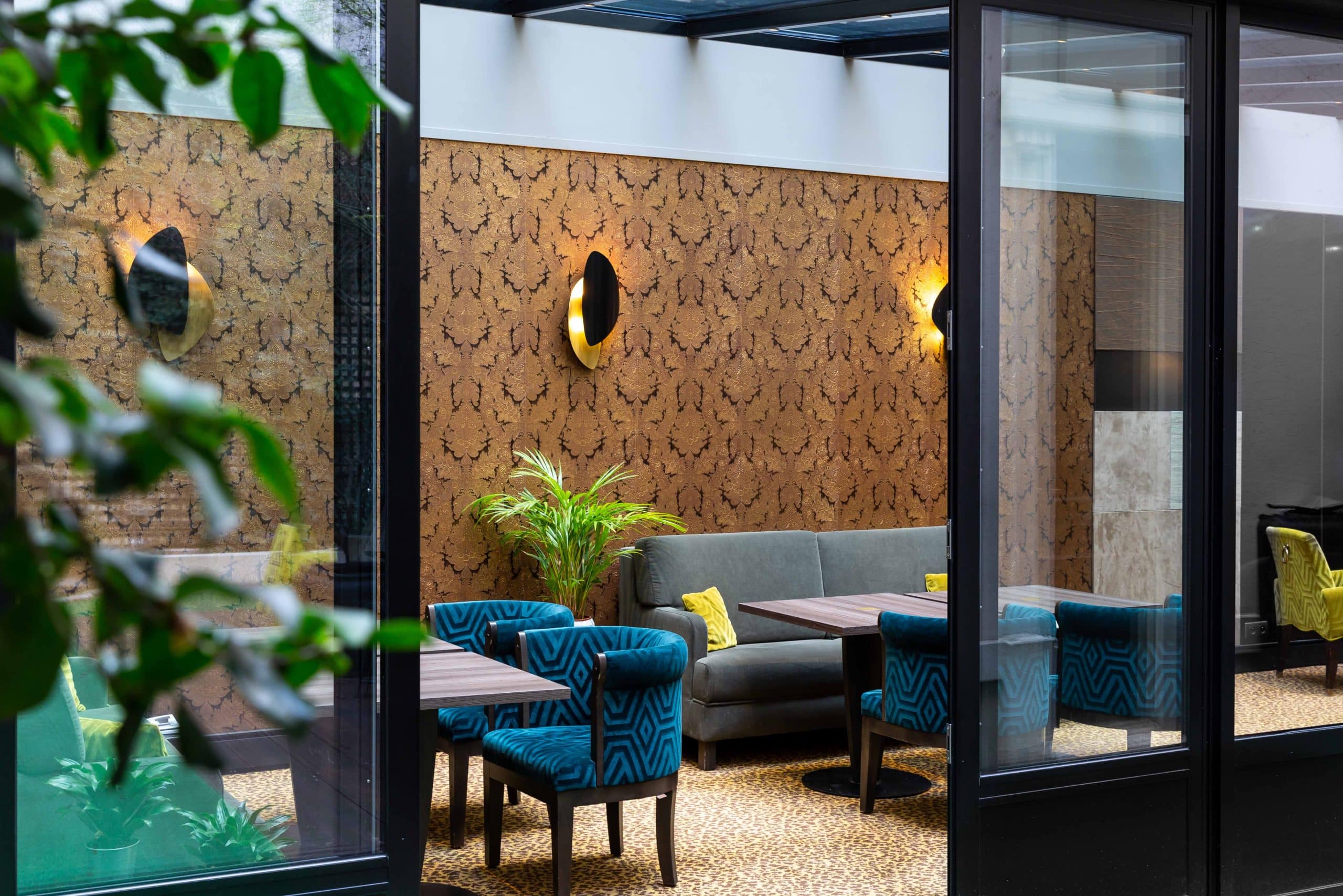 Espace lounge de la véranda de l'Hôtel Concortel vu depuis la cour