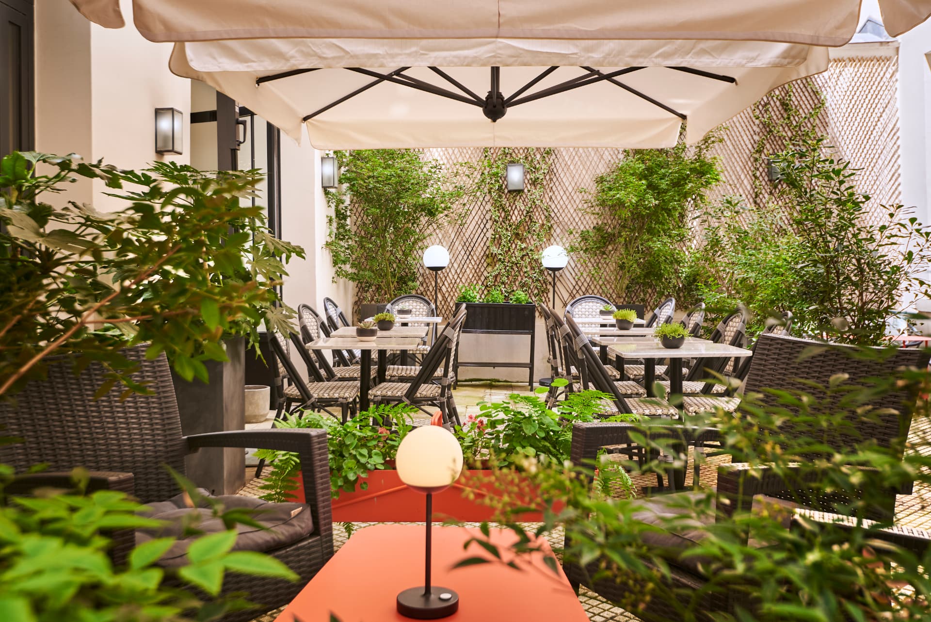 Patio du Mayflower : tables, treillage végétalisé et lanternes