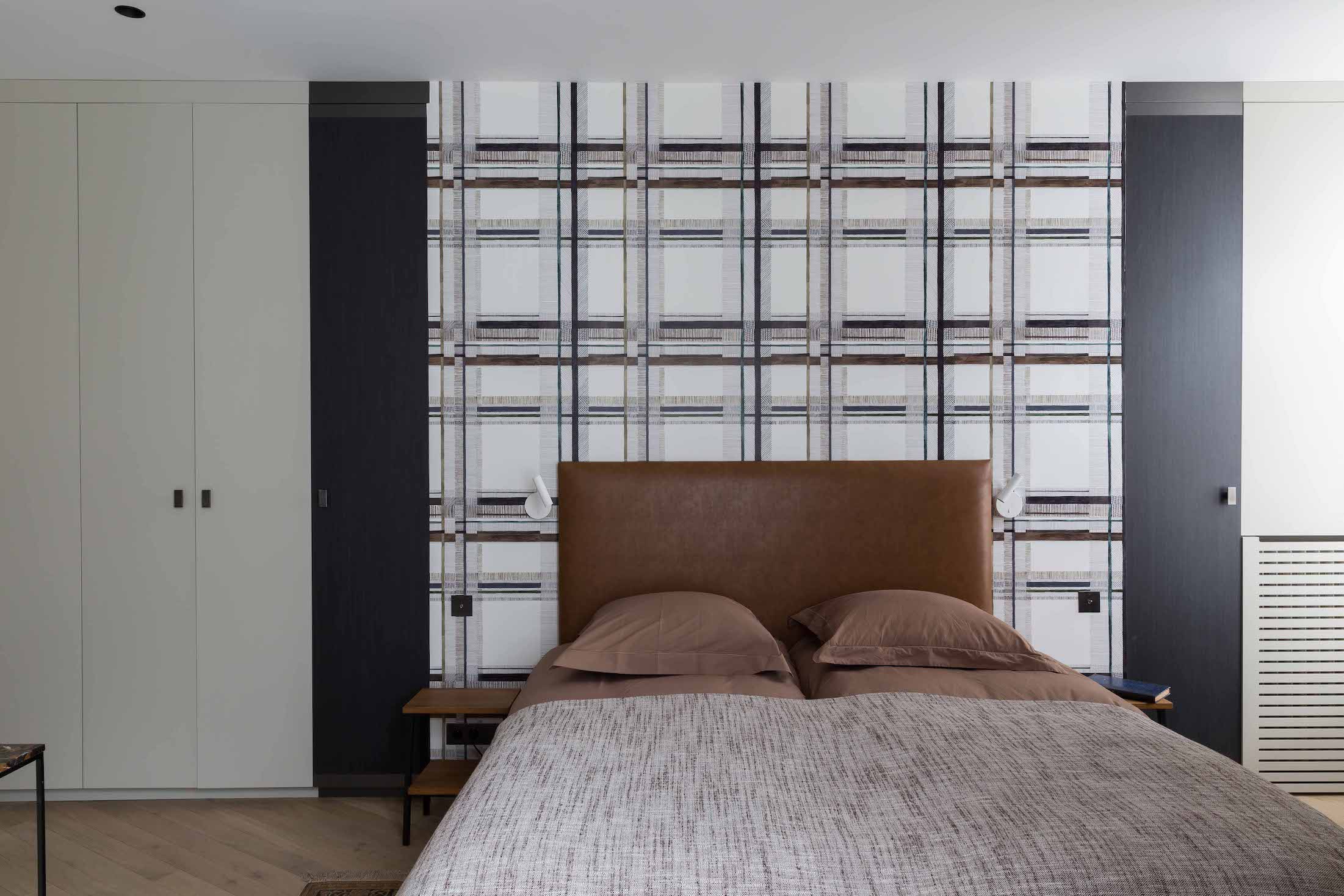 Chambre structurée par un mur de menuiserie à trame verticale et une paroi de rangements toute hauteur