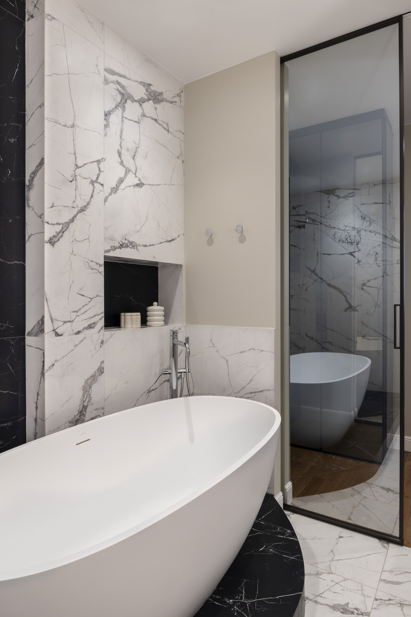 Baignoire îlot devant un mur de marbre veiné et niche de rangement