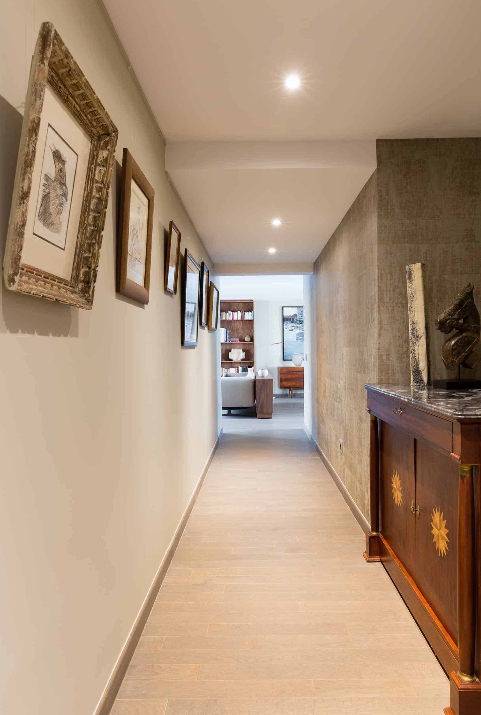 Couloir de distribution en enfilade, mur clair et enfilade de portes vers les pièces privatives