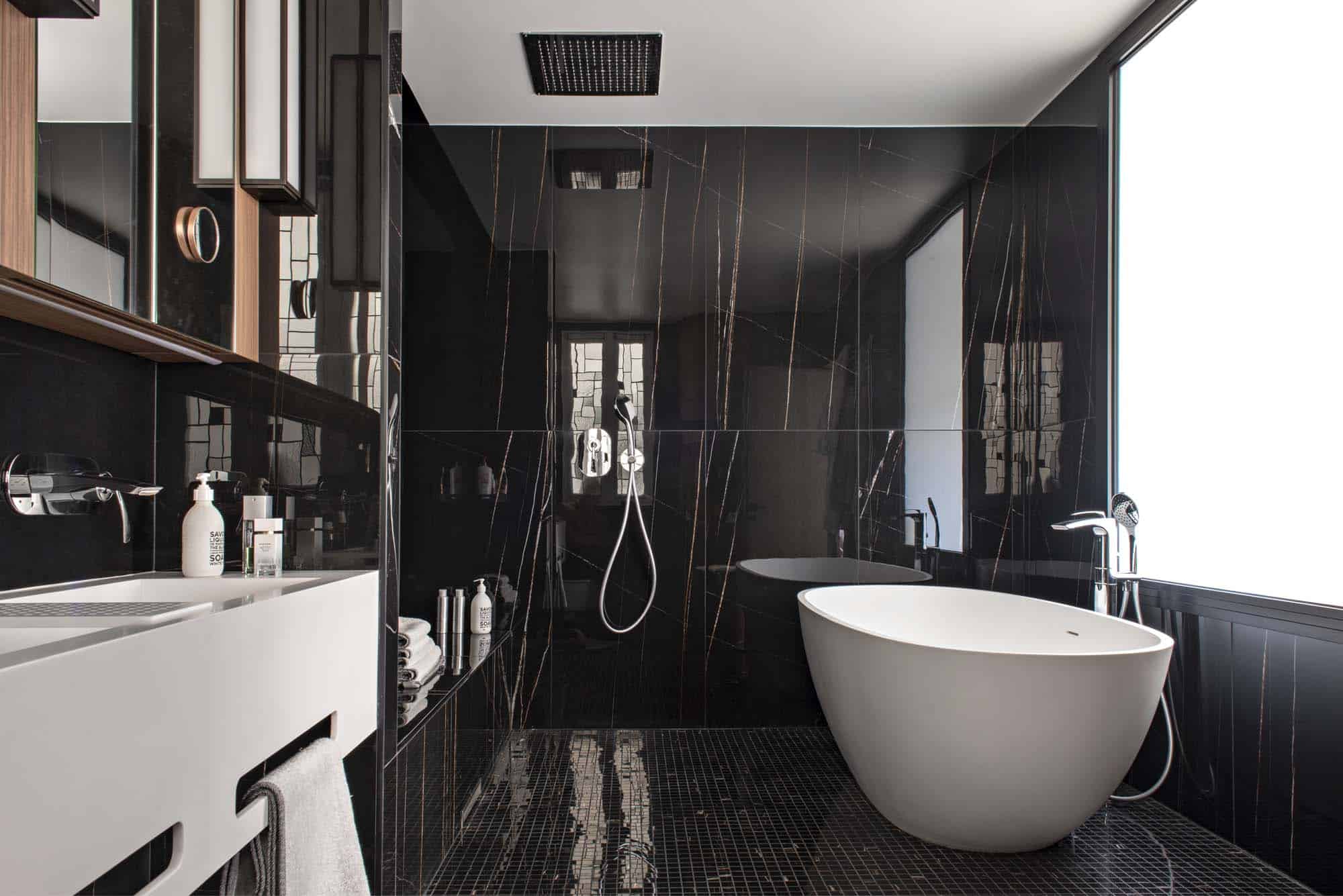 Salle de bains en marbre noir veiné, baignoire îlot et longue vasque sous miroir toute largeur