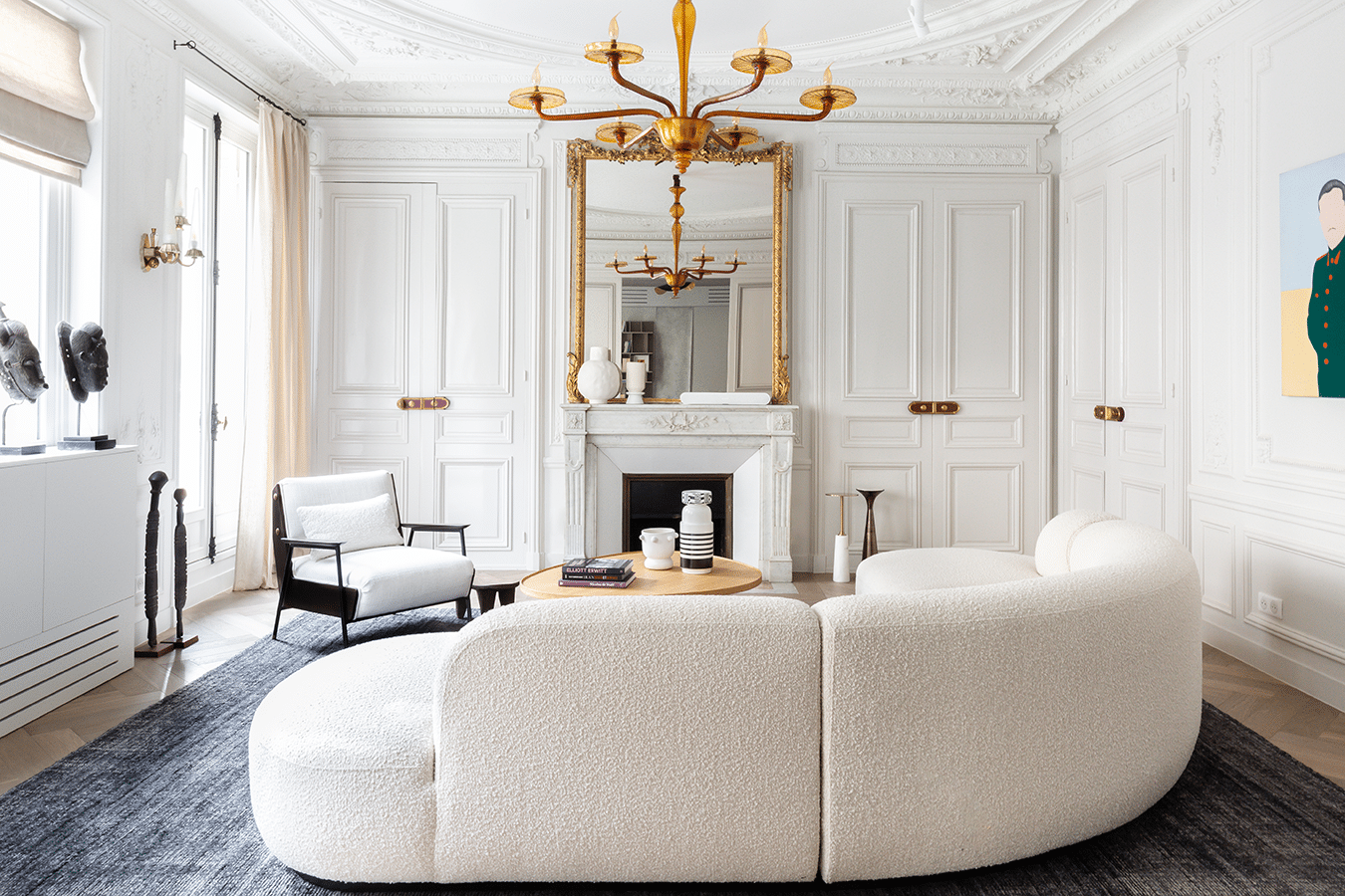 Enfilade des pièces de réception avec canapé bouclé courbe, miroir doré et cheminée de marbre
