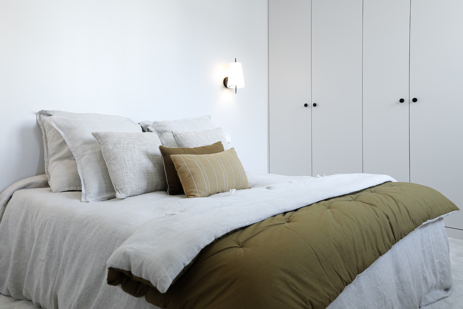 Chambre avec couvre-lit vert et rangements sur mesure